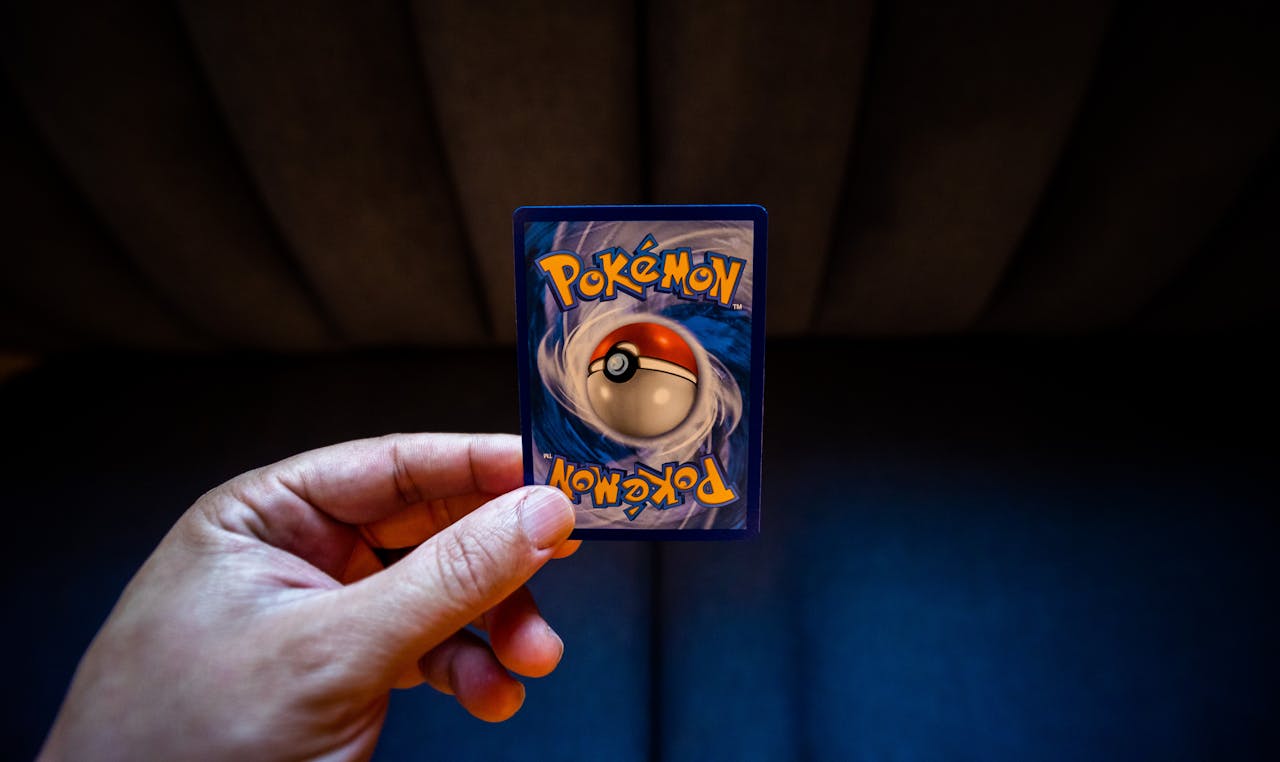 services-04 A hand holds a Pokémon trading card with a dark background, emphasizing gaming culture.